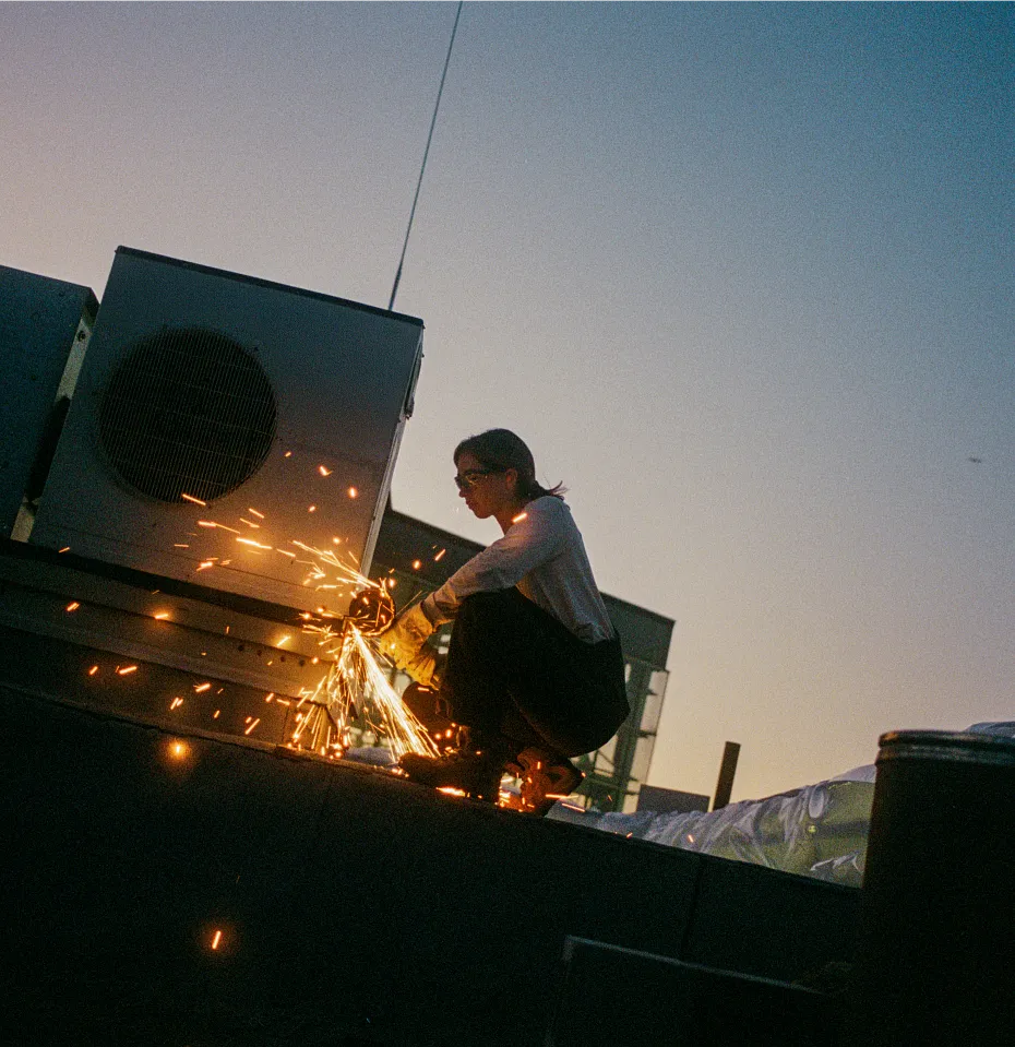 A woman at a work site using a grinder