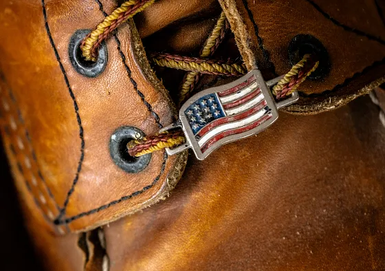 Close up of the laces of a boot with an american flag charm on it