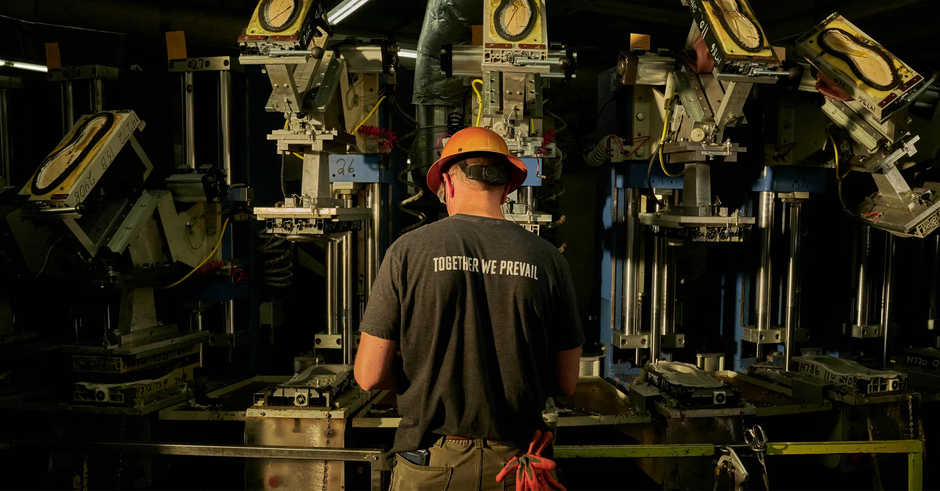 Man standing behind machinery wearing a Together We Prevail tshirt