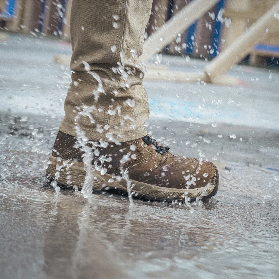 Closeup of person's lower leg with a boot on stepping in a water puddle