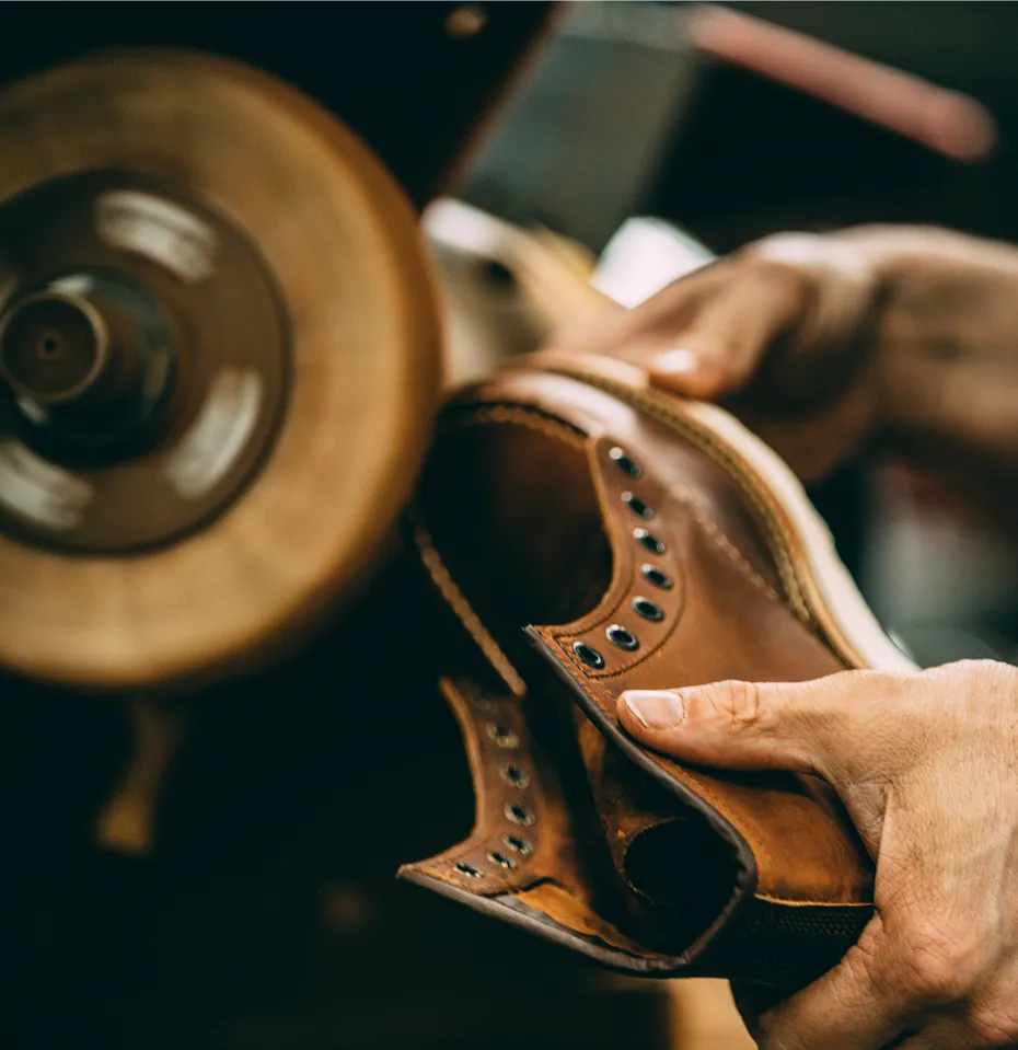 Close up of a person's hands holding a boot to a buffer machine