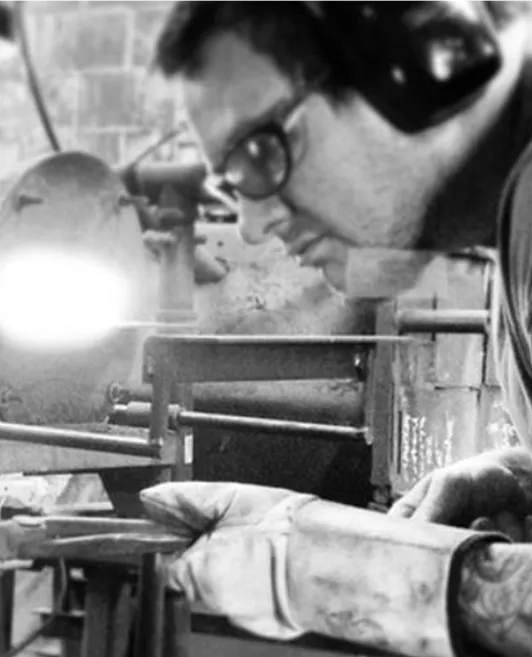 Black and white picture of Andrew R. Chambers Jr. working with metal in a shop