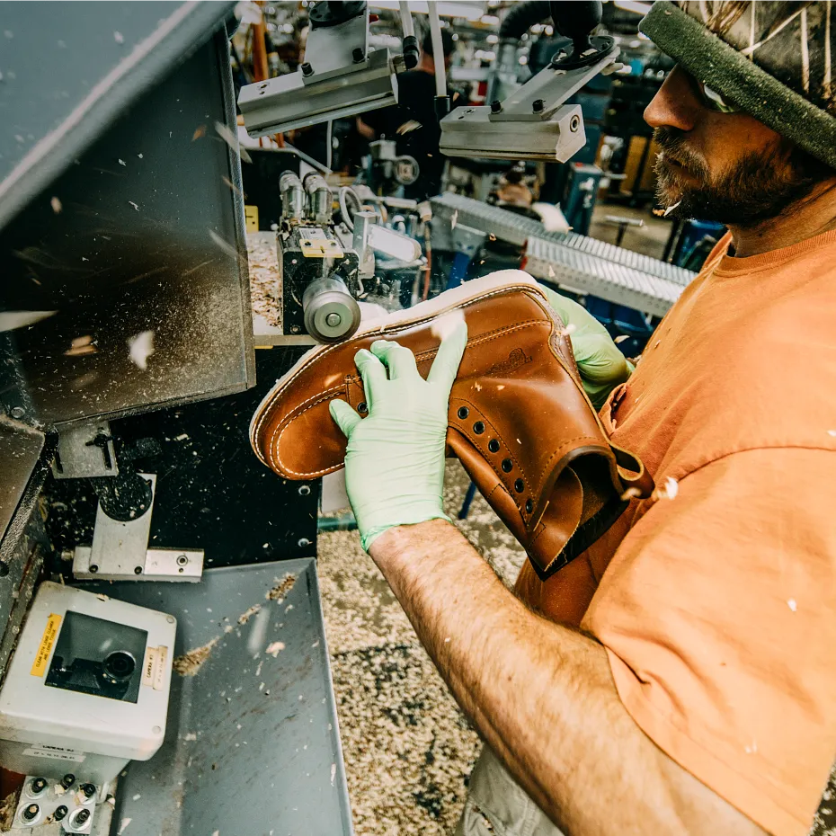 Close up of a man using a grinder on a boot in a workshop