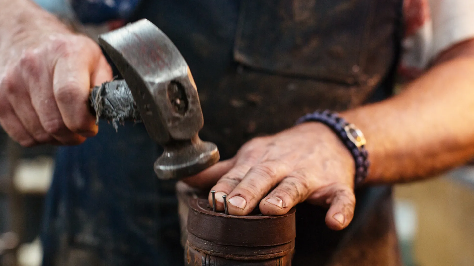 A man repairing boots with a hammer and nails