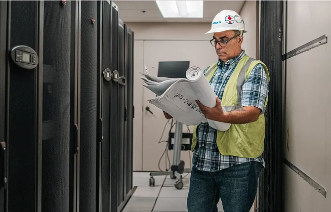Miguel A. Rueda reading spec sheets at a job site.