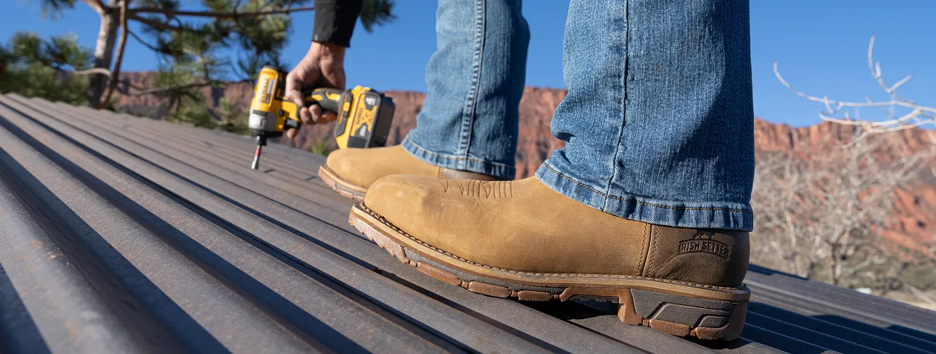 Person using a drill on a roof wearing Marshall boots