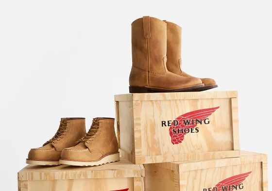 2 pairs of boots sitting on wood boxes against a white background