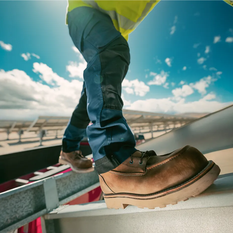 Closeup view of person's lower legs wearing boots and stepping on scaffolding