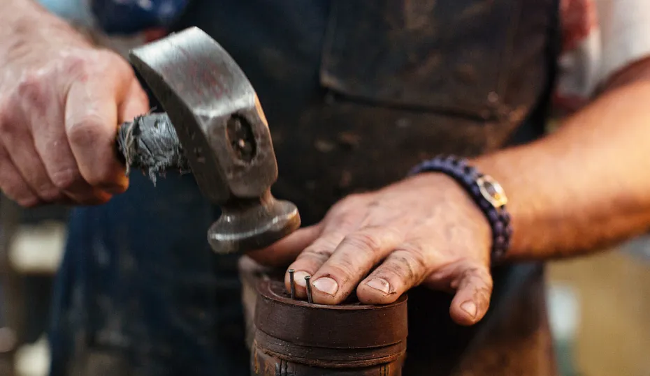 Close up of a person hammering nails into the sole of a shoe