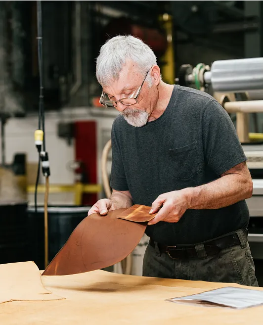 A man at a work bench comparing leather pieces