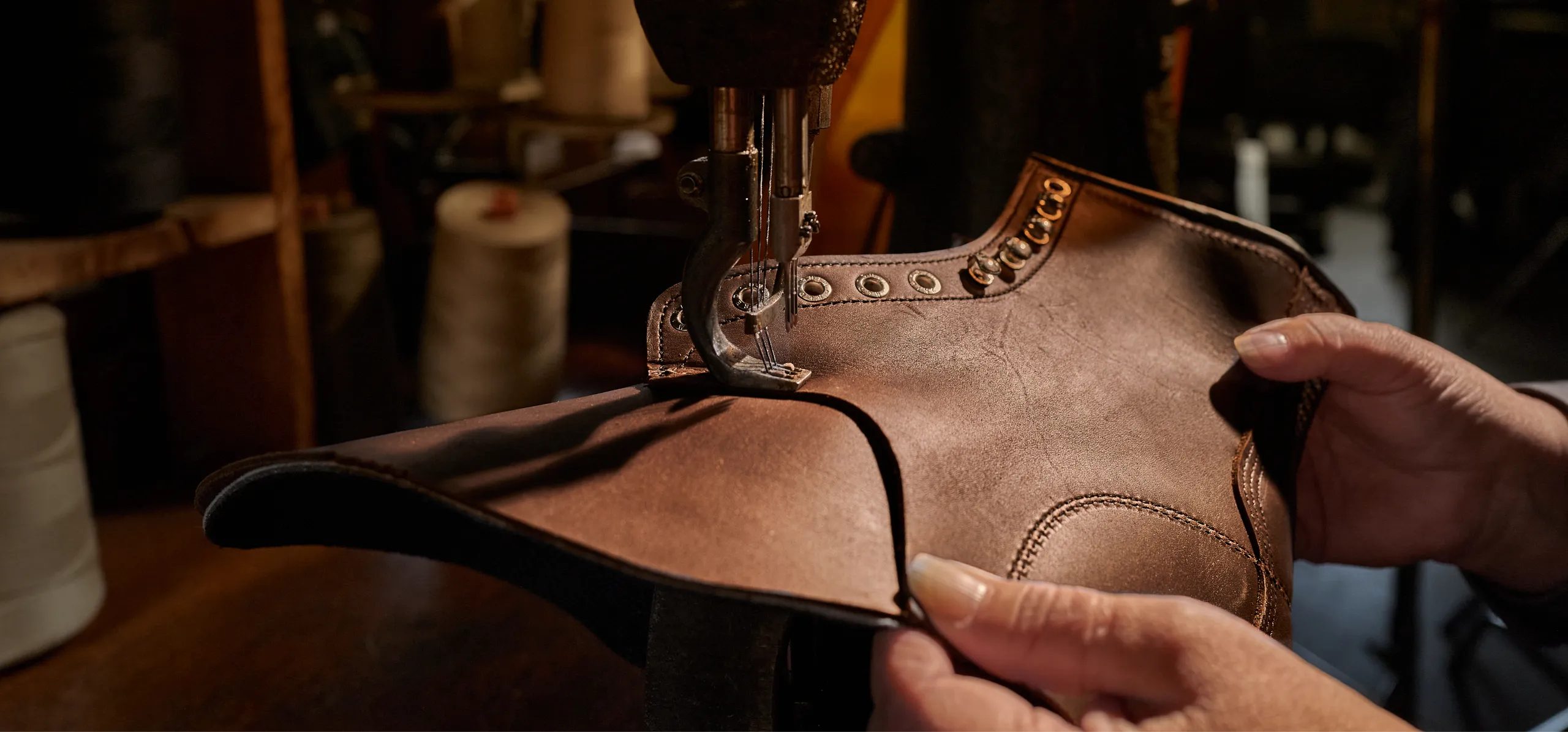Close up of a person hands holding a boot on a sewing machine
