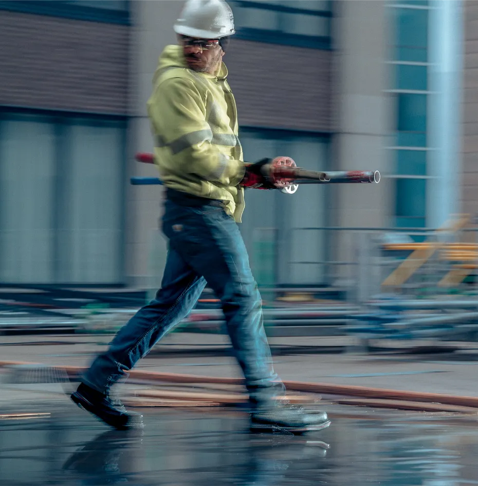 Man on worksite carrying metal poles
