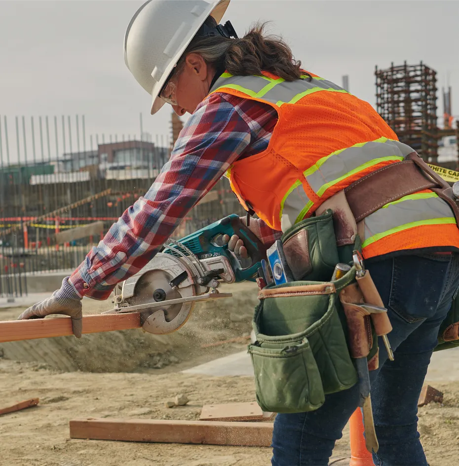 Woman working on a jobsite sawing boards