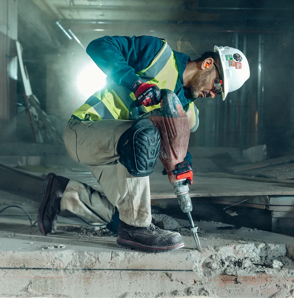 A man in workgear using a jackhammer at a jobsite