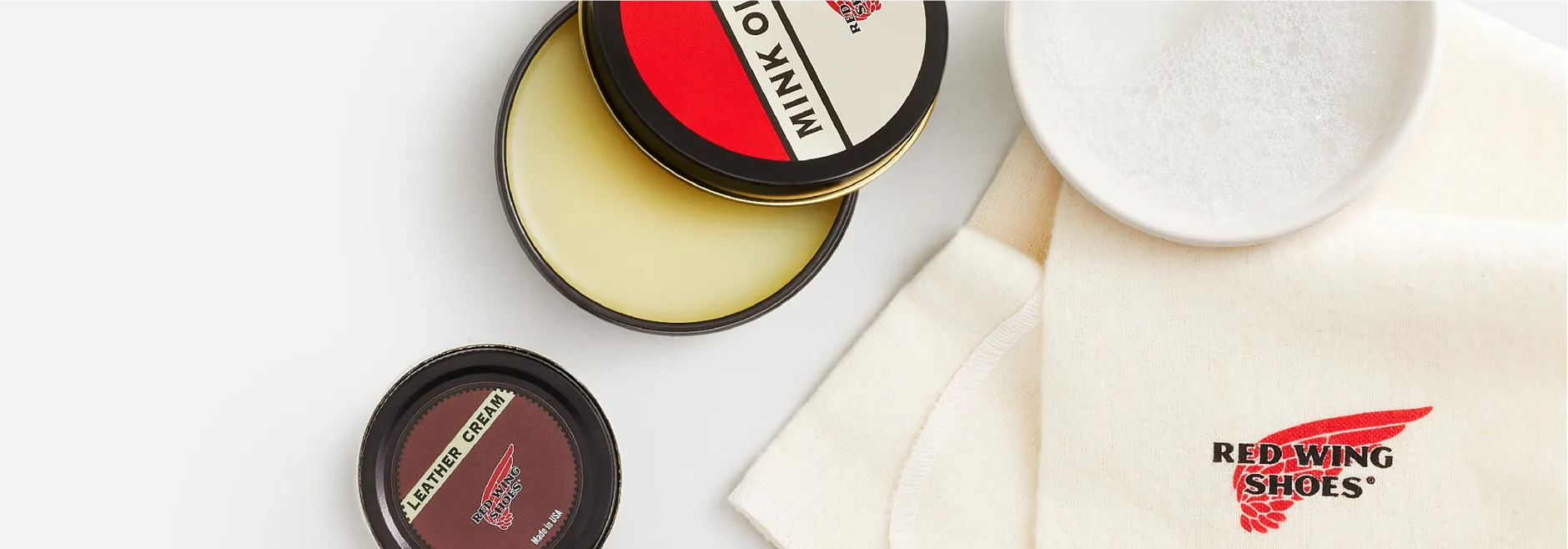Overhead view of Mink Oil and Leather cream tins with a cleaning cloth and dish of water