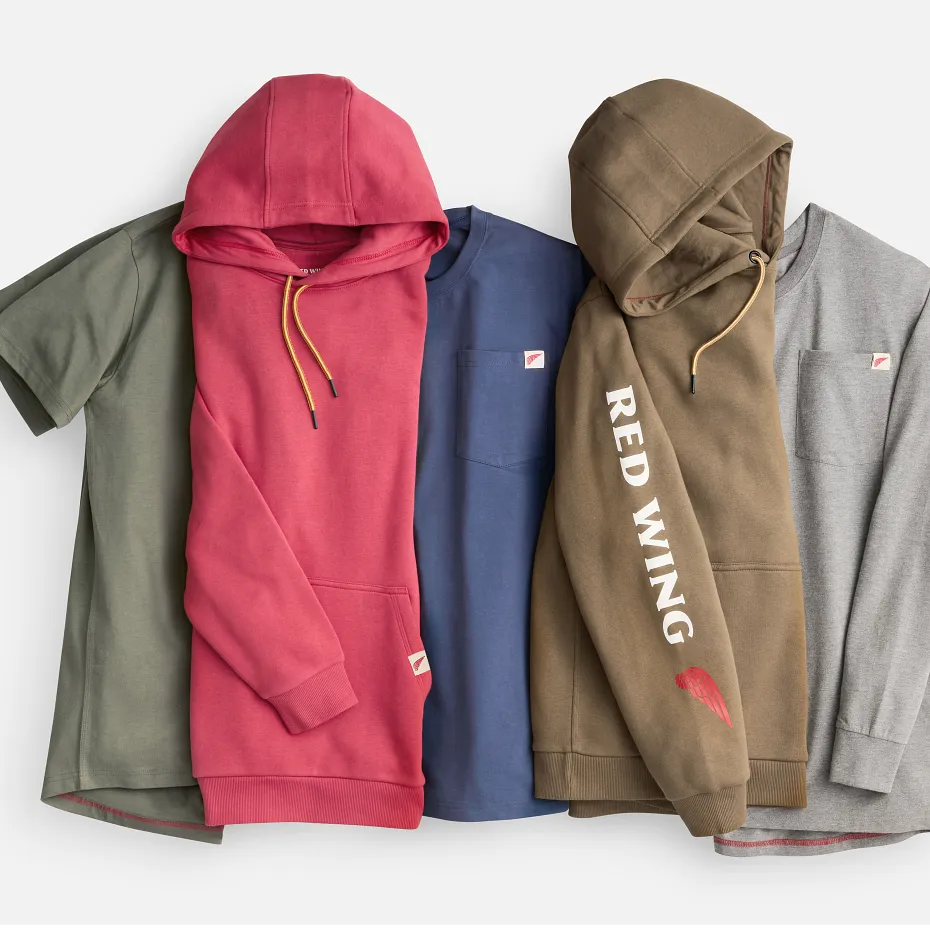 Assortment of tshirts and sweatshirts laying on a white background