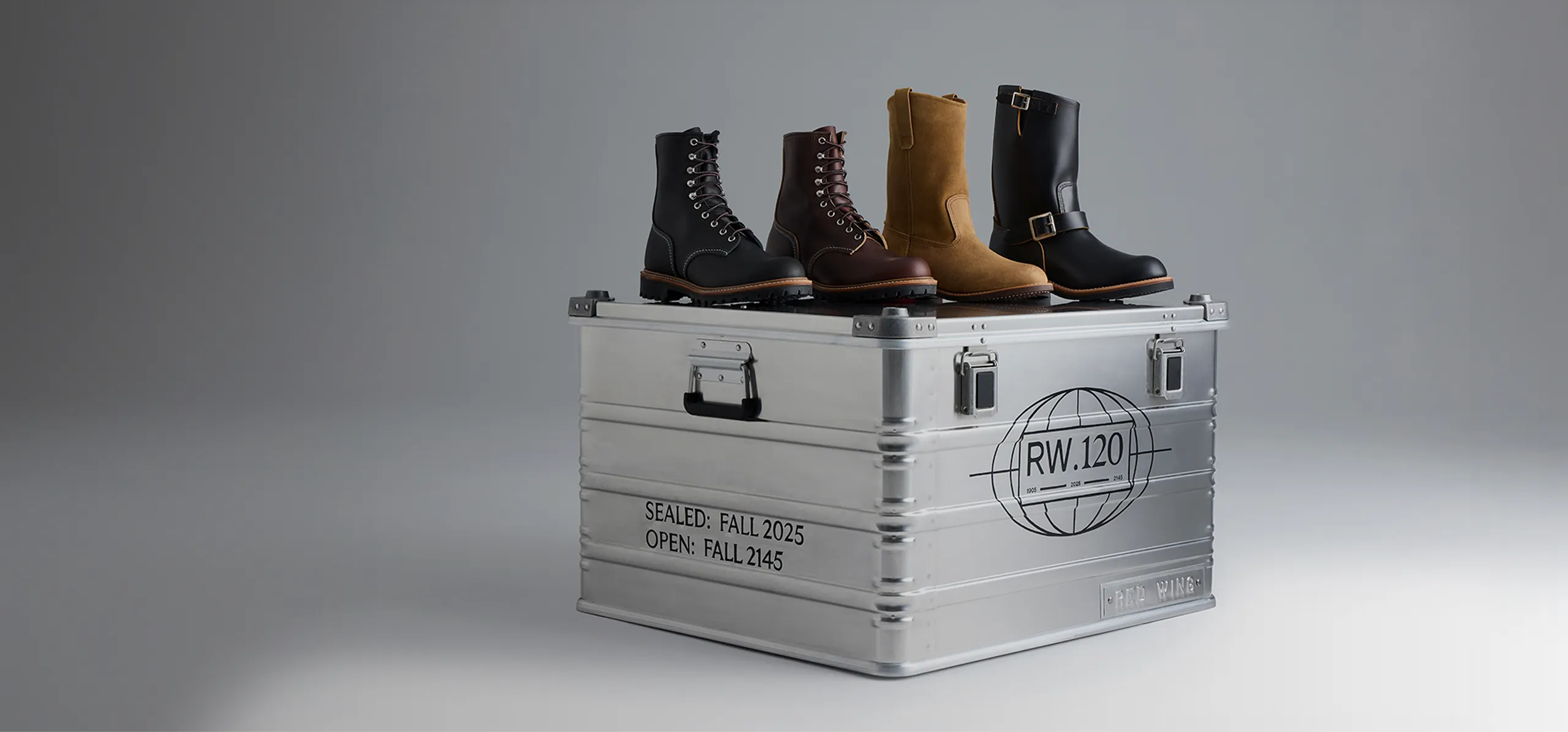 Four Red Wing boots sitting on top of a metal box against a white background 
