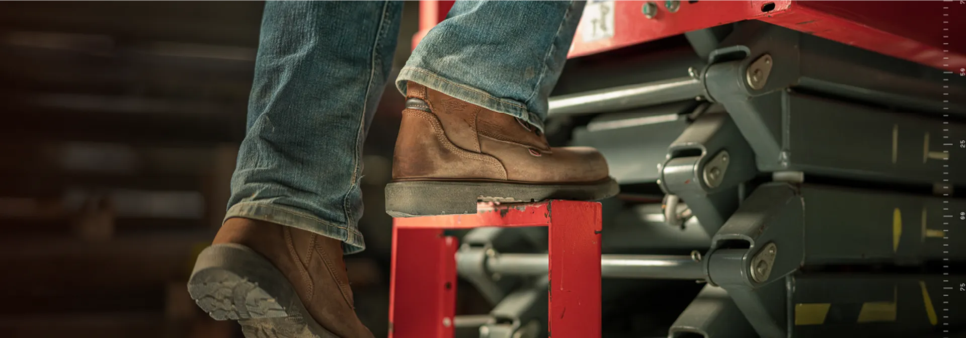 Close up of a person's boots climbing onto equipment