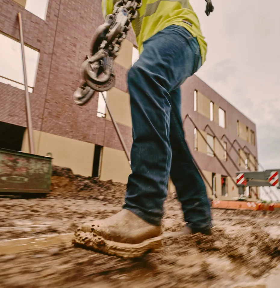 Worker walking through a muddy worksite carrying a chain