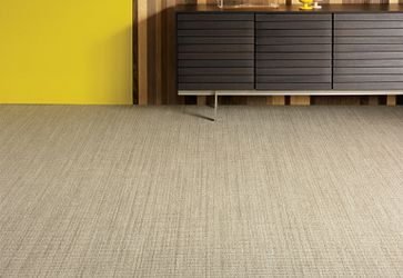 Modern interior with beige commercial carpet tile flooring, dark wood sideboard, and yellow accent wall
