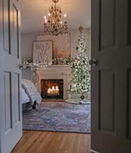 A Balsam Hill pre-lit Frosted Alpine Fir tree near a fireplace