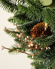 Nahaufnahme eines künstlichen Weihnachtszweigs mit naturgetreuen Nadeln und Dekorationen