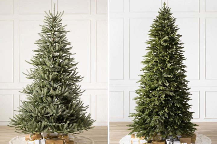 two unlit artificial Christmas trees in a white room