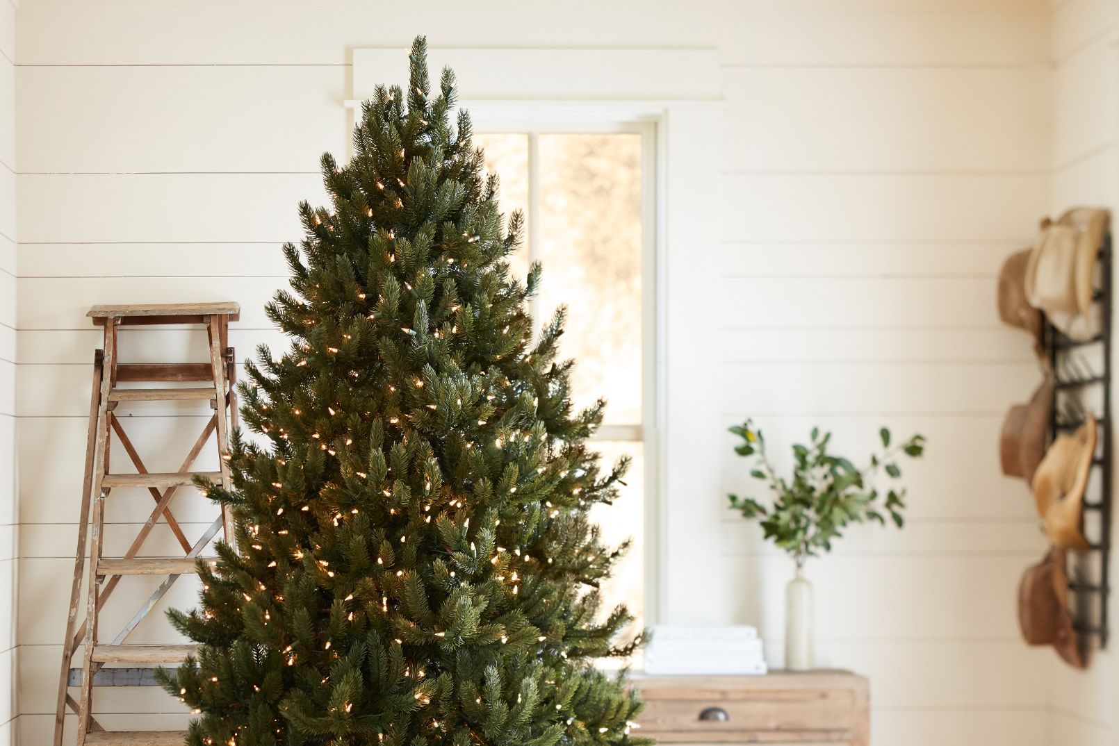 Künstlicher Baum mit weihnachtlicher LED-Beleuchtung in einem rustikalen Raum