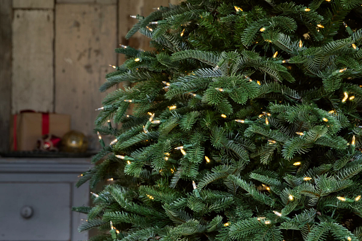 close-up of realistic artificial Christmas tree with clear LED lights