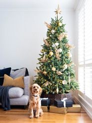 decorated artificial Christmas tree with a puppy in front of it