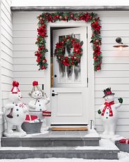a Christmas-themed wreath and garland on a white front door