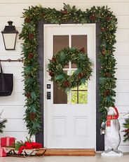 a Christmas-themed wreath and garland on a white front door