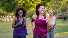Three young women jogging outdoors.