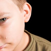 Young boy shown with a tear on his check.