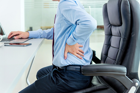 man with back pain at desk