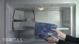Hands placing an icepack in the freezer