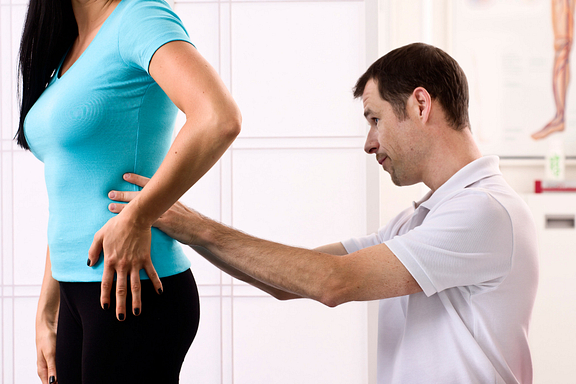 physical therapist examining patient's back