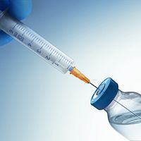 A syringe removing medicine from a bottle.