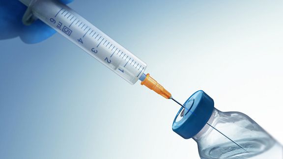 Syringe drawing a cortisone injection from a vial.