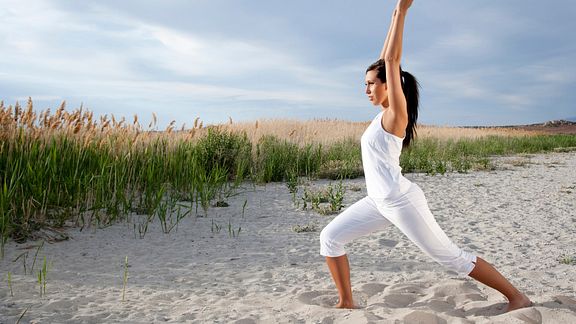 Woman performing yoga on the beach.