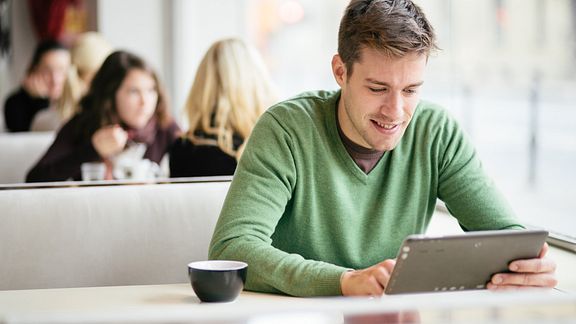 Young man reading tablet at a table in the coffee shop