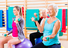 Image of seniors and instructor in an exercise class doing exercise ball exercises with hand weights