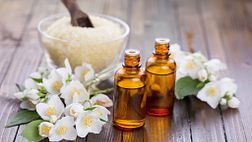 Bottles of essential oils alongside bath salts and flowers