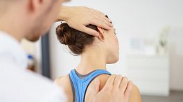 Male physical therapist massaging a young woman's neck in the medical office