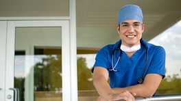 Surgeon standing outside leaning on a railing.