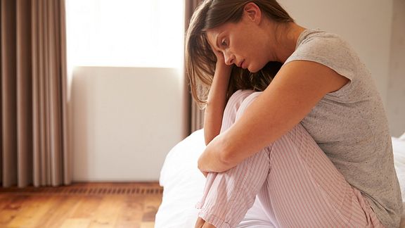 Depressed woman sitting on bed