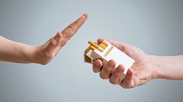Hand saying no to a pack of cigarettes.