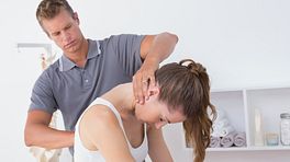 Male physical therapist examining a young woman's cervical and thoracic spine in the medical office