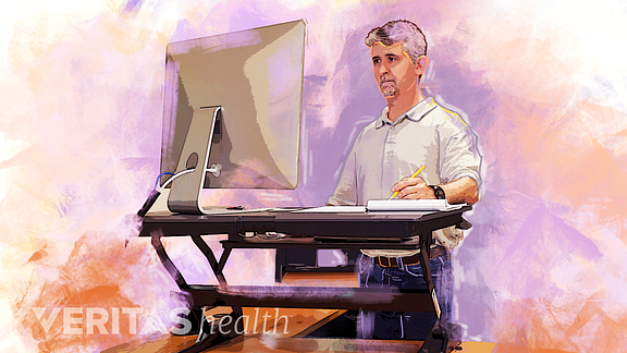 Illustration of a man using a standing desk converter in his office