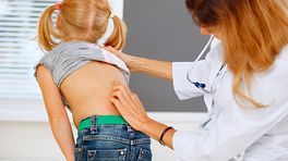 Doctor examining young patient's spine